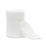 تصویر پدهای پنبه‌ ای گرد سفید مخصوص پاک کردن آرایش، به صورت یک دسته پد روی هم قرار گرفته و چند عدد جدا شده در جلوی آن